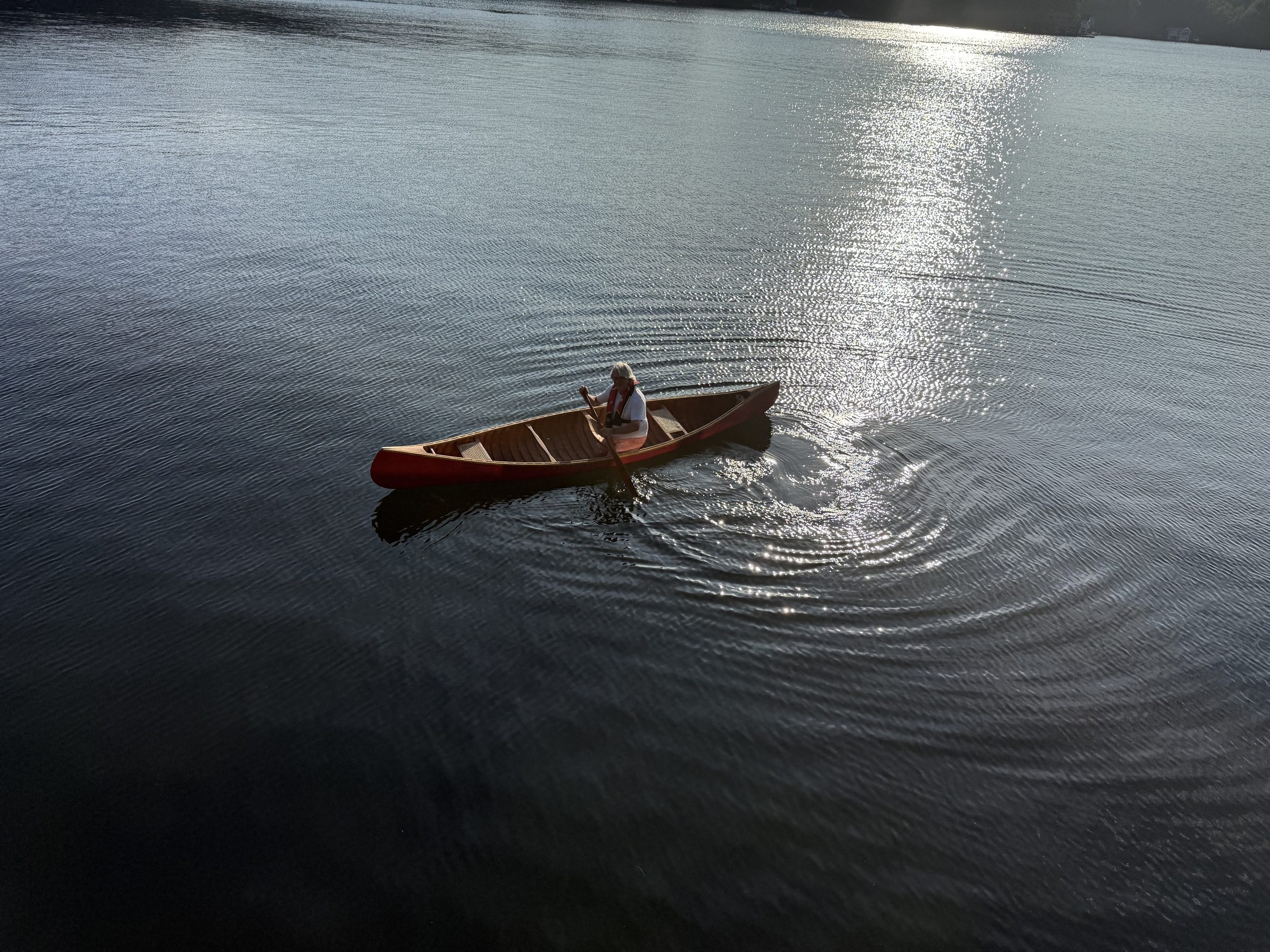Guy Burry paddling a canoe alone on a calm Muskoka lake in morning light
